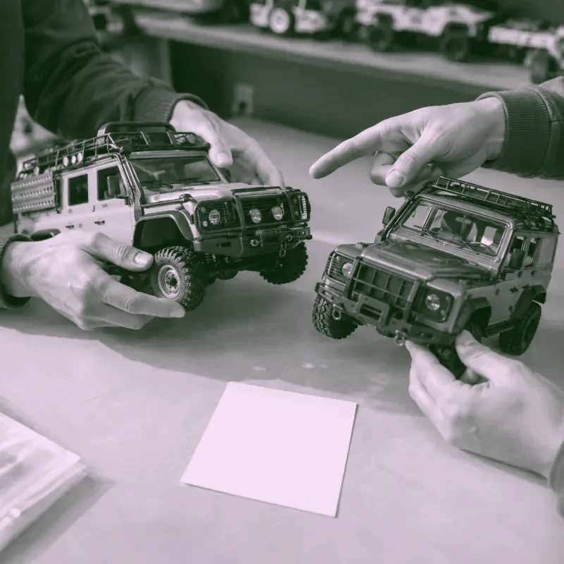 Dos personas comparando modelos RC sobre una mesa de trabajo